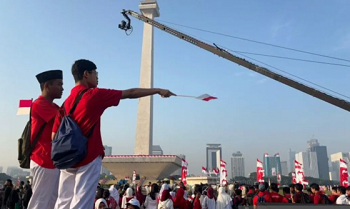 Masyarakat bersiap menyaksikan prosesi kirab bendera Merah Putih di depan pintu Cawan Monas sisi Utara, Jakarta Pusat, Minggu (17/8/2025).