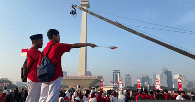 Warga Berpakaian Merah Putih Padati Monas 1 Masyarakat bersiap menyaksikan prosesi kirab bendera Merah Putih di depan pintu Cawan Monas sisi Utara, Jakarta Pusat, Minggu (17/8/2025).