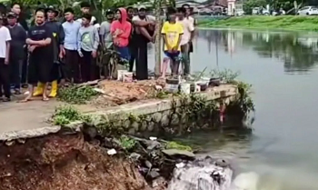 Warga menyaksikan kondisi tanggul sungai Kalimalang yang jebol di wilayah Telukjambe Barat Karawang